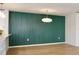 A modern dining area featuring a striking green accent wall, stylish lighting, and light wood floors at 2460 Formax Dr, Orlando, FL 32828