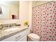 Bright bathroom featuring a floral shower curtain, granite countertop, and white cabinets at 2524 Harmonia Hammock Rd, Harmony, FL 34773