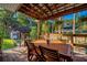 Inviting covered outdoor patio with wooden table, chairs, and lush landscaping at 302 Hermits Trl, Altamonte Springs, FL 32701