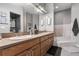 Bathroom with dual sinks, wood cabinets, and a separate tiled tub with step-up access at 32615 Windy Oak St, Sorrento, FL 32776