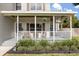 Inviting front porch with white railing, hanging plants and lush landscaping offering curb appeal at 32615 Windy Oak St, Sorrento, FL 32776