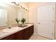 Bathroom featuring double sinks, granite counters, wood cabinets, and a large mirror at 3441 Hickory Creek Rd, Deltona, FL 32738