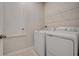 Laundry room featuring white appliances, base molding and a door on a tiled floor at 3586 Dahlia Dr, Lake Hamilton, FL 33851