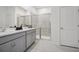 Bright bathroom with double sinks, gray cabinets, and a glass-enclosed shower with floor to ceiling tile at 3588 Dahlia Dr, Haines City, FL 33844
