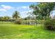 Spacious backyard with lush green grass, mature trees, a pond view and black metal fence at 408 Egret Place Dr, Winter Garden, FL 34787