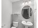 Powder room with pedestal sink, oval mirror, and views to staircase at 5006 Caspian St, St Cloud, FL 34771