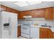 Functional kitchen featuring white appliances, tile backsplash, and warm wood cabinetry at 6095 Village Cir # 6095, Orlando, FL 32822