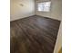 An empty bedroom with dark brown floors, a window and a white door and closet at 710 Ridenhour Cir # 710, Orlando, FL 32809