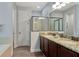 Bright bathroom featuring double vanities with granite counters, dark wood cabinets, and glass enclosed shower at 7519 Marker Ave, Kissimmee, FL 34747