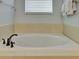A close-up of a clean, white bathtub with bronze fixtures, complemented by neutral tile and a nearby window at 7519 Marker Ave, Kissimmee, FL 34747