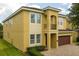 Side view of a two-story home with a brown garage door and manicured landscaping at 7519 Marker Ave, Kissimmee, FL 34747