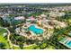 An aerial shot shows a resort-style pool with slides, surrounded by palm trees and lush landscaping, for relaxation and recreation at 7643 Wilmington Loop, Kissimmee, FL 34747