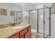 Bathroom featuring granite counters, wood cabinets, a framed mirror, and a glass enclosed shower at 7643 Wilmington Loop, Kissimmee, FL 34747