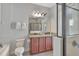 Bathroom with double vanity, granite counters, and a tiled shower with glass enclosure at 7643 Wilmington Loop, Kissimmee, FL 34747