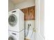 Laundry room with stacked washer and dryer, wood cabinets, and tile floor at 807 Ayden Oak Ln, Ocoee, FL 34761