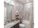 Bathroom with granite countertop, framed mirror, and shower with patterned tile surround at 112 Red Maple Burl Cir, Debary, FL 32713