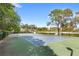 Community tennis court surrounded by mature trees on a sunny day at 12843 Madison Pointe Cir # 106, Orlando, FL 32821