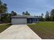 New single-story home with blue exterior, gray roof, and a spacious concrete driveway at 15259 Sw 51St Cir, Ocala, FL 34473