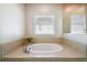 Luxurious soaking tub in a neutral-toned bathroom with a tiled surround at 1816 Forest Glen Dr, Fruitland Park, FL 34731