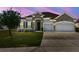 Charming single-story home with a two-car garage, stone accents, and a well-maintained lawn at twilight at 1816 Forest Glen Dr, Fruitland Park, FL 34731