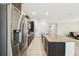 An open kitchen boasts stainless steel appliances, dark cabinets, light tile floors, and an expansive granite island at 1816 Forest Glen Dr, Fruitland Park, FL 34731