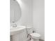 Bright half bathroom featuring a pedestal sink, round mirror, and a standard toilet at 2170 Derwent Dr, Davenport, FL 33896