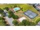 Aerial view of community amenities, including a pool, tennis court, and parking area, surrounded by trees at 2170 Derwent Dr, Davenport, FL 33896