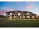 Stately brick home featuring a well-manicured lawn and covered front porch at twilight at 240 Spring Forest Dr, New Smyrna Beach, FL 32168