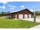 Exterior view of large outbuilding with multiple garage doors, basketball court, and expansive lawn at 240 Spring Forest Dr, New Smyrna Beach, FL 32168