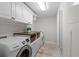 Bright laundry room with washer, dryer, cabinets, countertop, and tiled floors at 2602 Winter Park Rd, Winter Park, FL 32789