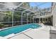 A screened-in pool with clear water and outdoor furniture, surrounded by lush landscaping at 2611 Burwood Ave, Orlando, FL 32837