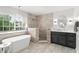 Bathroom featuring a freestanding tub, walk-in shower, dark cabinetry, and decorative lighting at 2644 Slagrove Ct, Winter Garden, FL 34787