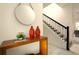 Entryway featuring a wooden console table, decorative vases, round mirror, and a staircase with black railings at 3009 Penelope Loop, Kissimmee, FL 34746