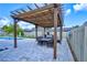 A covered pergola features a dining set with an outdoor kitchen, perfect for entertaining with a lush green backdrop at 3532 Amaca Cir, Orlando, FL 32837