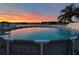 Above-ground pool with sunset reflection, palm tree, and white vinyl fence at 3680 Ricky Ln, St Cloud, FL 34772