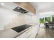 Contemporary kitchen with sleek cooktop, stainless steel range hood, and hexagonal tile backsplash at 4065 Winderlakes Dr, Orlando, FL 32835