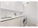 Laundry room with sink, modern faucet, sleek counter, and front-loading washer and dryer at 4065 Winderlakes Dr, Orlando, FL 32835