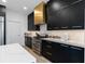 Sleek kitchen featuring black cabinets, stainless steel appliances, and a stunning gold range hood at 4509 Patricia Ann Ct, Orlando, FL 32839