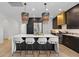 Open kitchen with island seating, black cabinets, stainless steel appliances, and unique pendant lighting at 4509 Patricia Ann Ct, Orlando, FL 32839