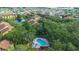 Aerial view featuring community pool nestled among mature trees with apartment buildings in the background at 5283 Images Cir # 308, Kissimmee, FL 34746