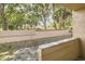 Enclosed patio with view of palm trees and grass, bordered by a concrete wall and black iron fence at 5321 Vineland Rd # 101, Orlando, FL 32811