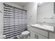 Clean bathroom with a single vanity, toilet, and bathtub featuring a stylish gray and white striped shower curtain at 555 Meadow Bend Dr, Davenport, FL 33837