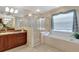 Well-lit bathroom features a shower with glass door, soaking tub, and vanity with a sink at 609 Westview Dr, Minneola, FL 34715