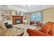 Cozy living room featuring a fireplace, comfortable seating, large window, and ceiling fan for a relaxing atmosphere at 609 Westview Dr, Minneola, FL 34715