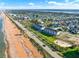 Scenic aerial shot of a coastal road lined with homes and condos, bordering a pristine sandy beach and the ocean at 7 Marden Dr, Ormond Beach, FL 32176