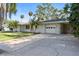 Charming home featuring a two-car garage and a well-maintained lawn with palm trees at 7046 Treasure Island Rd, Leesburg, FL 34788