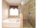 Bathroom featuring a tub, tile shower with glass door, and a window with blinds at 7407 Country Run Pkwy, Orlando, FL 32818