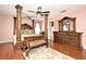 Elegant bedroom boasting a four-poster bed, hardwood floors, and a wooden dresser with mirror at 7407 Country Run Pkwy, Orlando, FL 32818