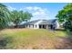 Rear view of the house showcasing the large backyard, covered patio, and well-maintained landscaping at 8004 Village Green Rd, Orlando, FL 32818