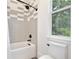 Bright bathroom featuring bathtub with shower, gray patterned tile, and window at 833 Dartmouth St, Orlando, FL 32804